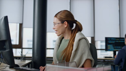 Happy developer typing computer in startup company. Smiling woman coder working