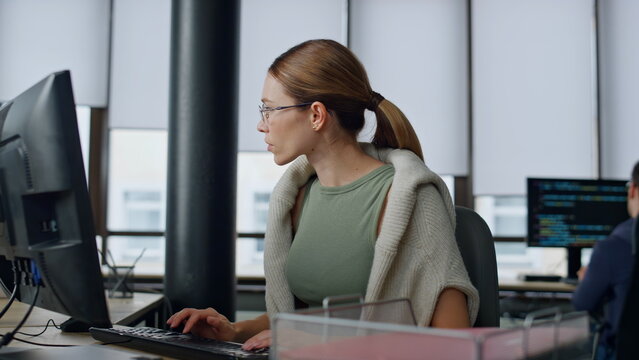 Software manager typing computer in office. Upset woman developer solve problem