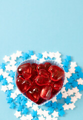 Muffin molds with red hearts and candy sprinkles on blue.