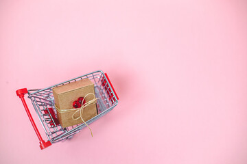 Mini cart and craft box with a red heart on a pink background.