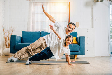 A father and his daughter create a harmonious family moment as they practice yoga at home...