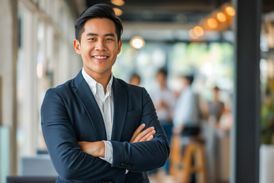 Portrait of a handsome smiling Asian businessman boss in a suit standing in a modern business company office