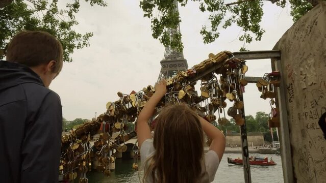 Unknown kids touch love locks or padlocks as love symbols close to the Eiffel Tower, Paris