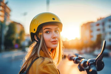 Rolgordijnen Young woman driving electric scooter in city, wearing yellow helmet. Sunset © VisualProduction