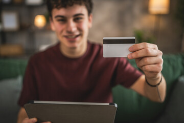 teenager young man sit at home use credit card shopping online
