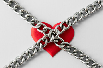 Red heart and metal chains. Minimal concept of domination, manipulation and abuse in relations....
