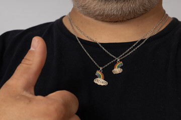 two rainbow pendants with a cloud and the inscription best friends around the neck of a man