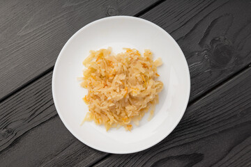 Sauerkraut on a white plate against a dark wooden background