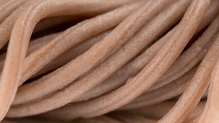Extreme close-up of brown noodles texture, very detailed, no additional food items visible.