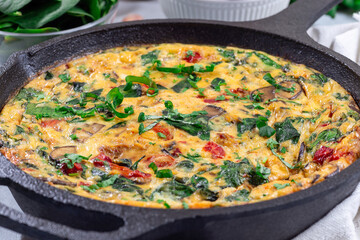 Egg frittata with spinach, roasted peppers, mushrooms, cheese, in cast iron, horizontal, closeup