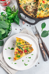 Piece of brunch egg frittata with vegetables on plate, vertical, top view