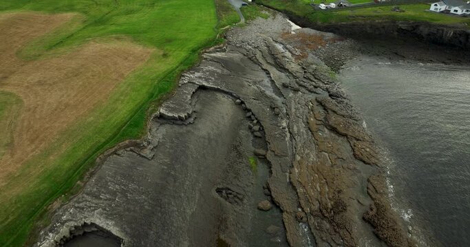 Rocky coastline near green fields in 4k
