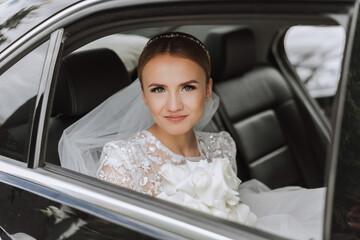 The bride looks out of the car window. Close-up portrait of a pretty shy bride in a car window. Bride smile emotions
