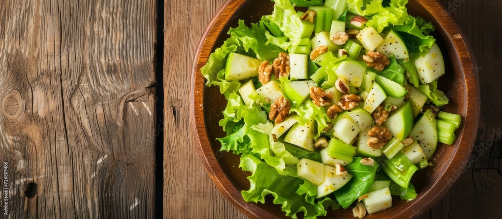 Wall mural top-down view of a wooden table showcasing a crisp waldorf salad comprising of lettuce, green apples