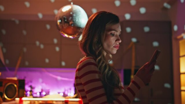 Upset lady reading message at smartphone in empty party room close up. Sad woman