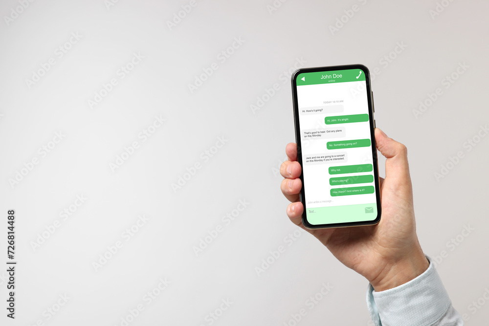 Poster man texting with friend using messaging application on smartphone against light grey background, clo