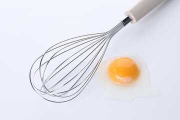 Whisk and raw egg isolated on white