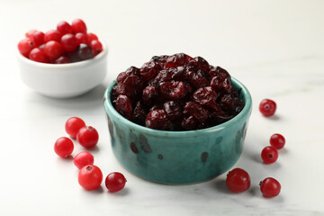 Tasty dried cranberries and fresh ones on white table, closeup