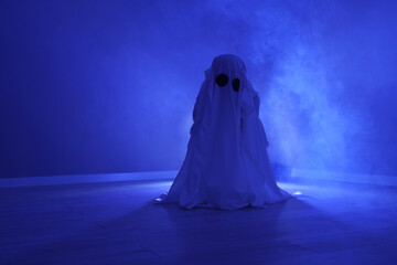 Creepy ghost. Woman covered with sheet in blue light