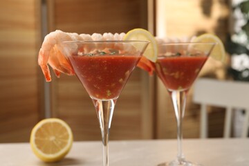 Tasty shrimp cocktail with sauce in glasses and lemon on light table