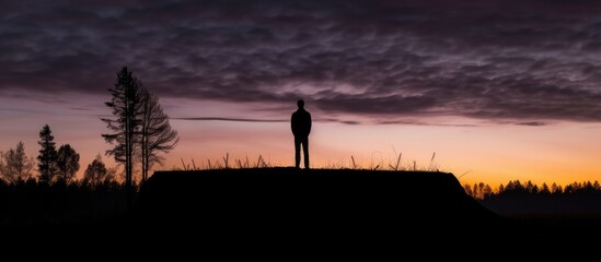 Silhouette of a man standing on top of a hill.
