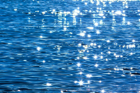 Blue water surface with sun rays and bokeh, abstract background