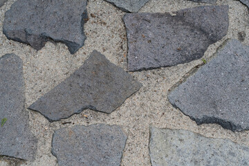 Looking down at a old outdoor granite patio rock with large grout lines.