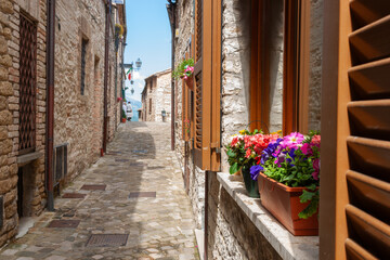 View along narrow European village street with sun on one side between homes and buildings