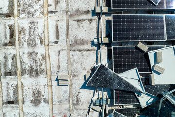 Top view of destroyed by hurricane Ian photovoltaic solar panels mounted on industrial building roof for producing green ecological electricity. Consequences of natural disaster in Florida