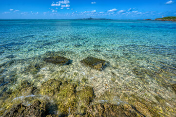 Naklejka na ściany i meble Crystal clear waters of Bise Beach, Motobu District, Okinawa main island. White sand beach with coral outcrops and small islands offshore