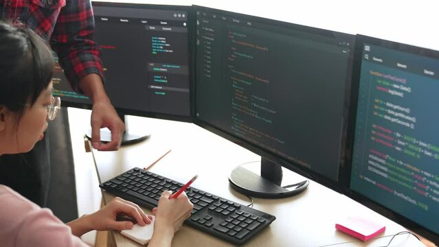 Back end or software developer manager supervising his team on new application program development on debugging and solving complex code algorithms on monitor. Burgeoning