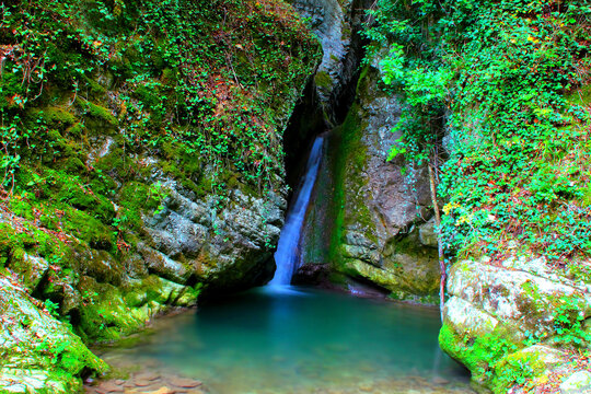 Ambrosial scene from the Sibillini Mountains with Cascata del Pellegrino in a long-exposure shot, the creamy waters of the scant waterfall merging with a mirror-like almost transparent body of water