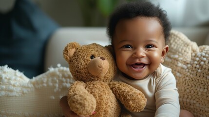 a very cute little black baby smiling, sitting up holding a stuffed bear. 