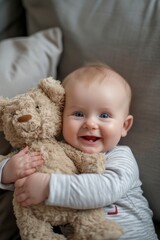 a very cute little blue eyed baby smiling, sitting up holding a stuffed bear. 