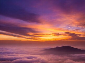 Fototapeta premium View from a mountain through the clouds. View from on airplane, at sunrise. Beautiful travel wallpaper. Orange dawn. Sense of freedom.