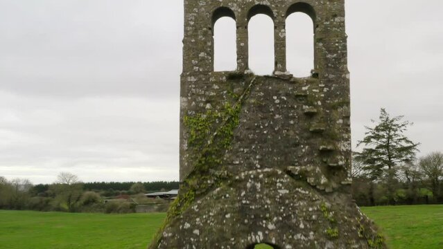 Drone descends pullback along old mossy bell tower and church wall remnants