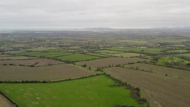 Lush green agriculture fields lined by trees with Dublin City Centre in the distance