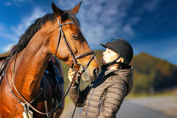 Horse head portraits in front of a blue sky and a rider standing next to it..