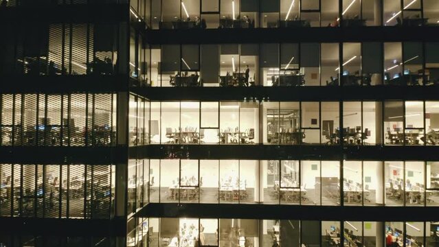 Aerial view of Windows in a high-rise office building late at night with interior lights glowing and flashing. Corporate offices.Night view Skyscraper with night lights and workers working until late