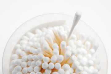 Cotton swab for cleaning ears on a blurred background of a glass of sticks with selective focus and copy space