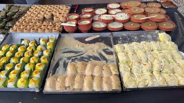 Profile view of Firni, sandesh, chamchams and other sweets kept on a aluminum plates in Kolkata, India.