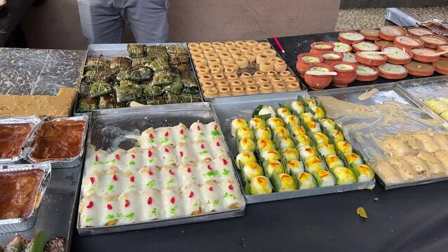 Parallax shot of many different kind of traditional Bengali sweets kept beside each other during daytime in Kolkata, India.