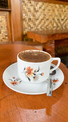 a cup of excelsa coffee on old wooden background. Traditional white cup of Indonesia. Banyuwangi coffee