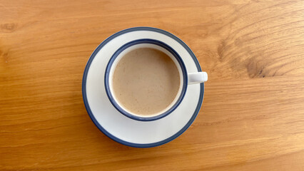 A cup of milk coffee isolated wooden table background on a white cup. Banyuwangi coffee