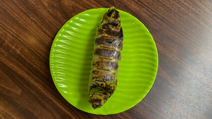 Nasi bakar daun or grilled rice on banana leaves isolated on cement background. This rice is wrapped by using banana leaf and then roasted by using charcoal. Ingredients with seafood, meat, chicken
