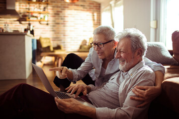 Senior couple using a laptop at home in the living room