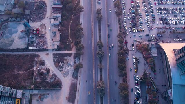 Aerial from the top view of a busy road with a Metro station next to a parking lot in Islamabad, Pakistan