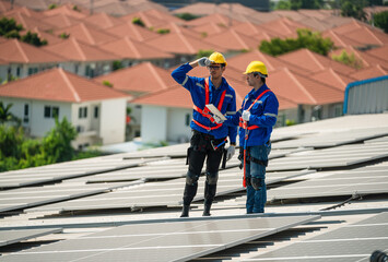 Men technicians carrying photovoltaic solar modules on the factory roof. Engineers in helmets installing solar panel systems outdoors. Concept of alternative and renewable energy solar cell.