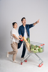 Image of Asian couple pushing supermarket cart while shopping, isolated on white background © Q88