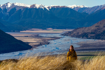pretty hiker girl admiring the panorama of waimakariri river valley and snow capped mountains in...